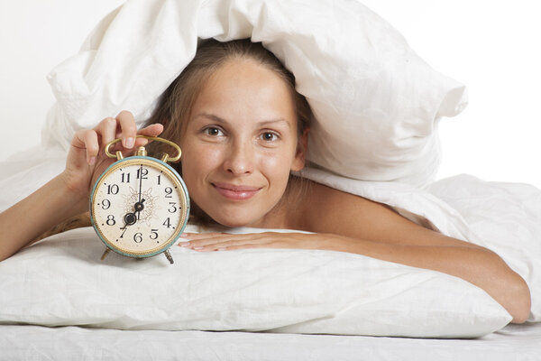Молодая женщина с будильниками на кровати по утрам

