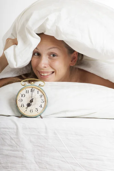 Femeie tânără cu ceas cu alarmă pe pat dimineața — Fotografie, imagine de stoc