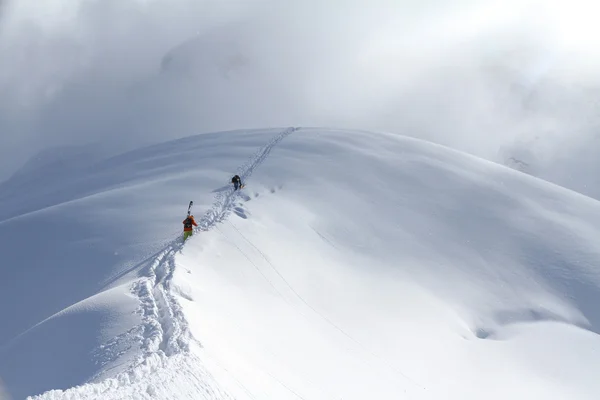 雪に覆われた山に登るスキーヤー — ストック写真