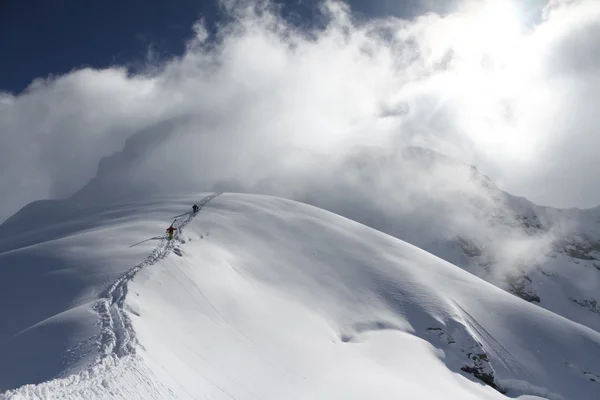 雪に覆われた山に登るスキーヤー — ストック写真