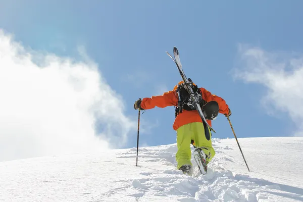 Esquiador escalando una montaña nevada — Foto de Stock