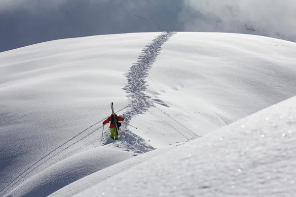 Skifahrer erklimmt einen verschneiten Berg — Stockfoto