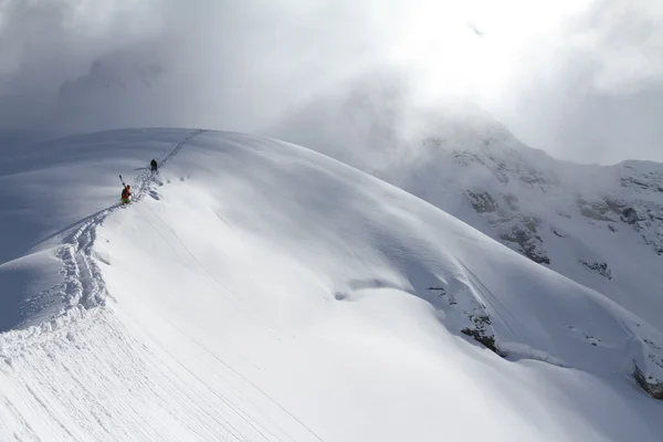 Esquiadores escalando uma montanha nevada — Fotografia de Stock