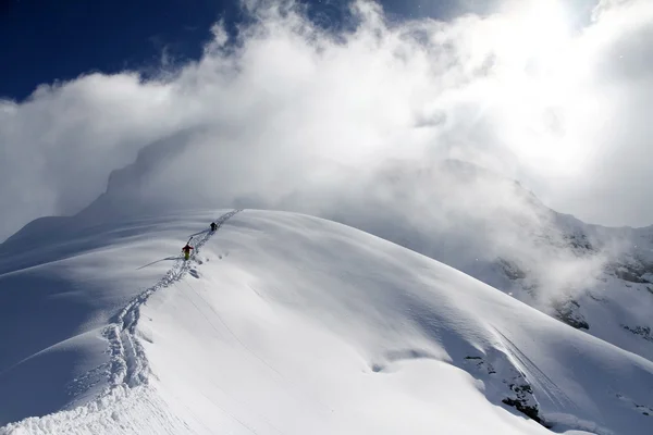 Esquiadores escalando uma montanha nevada — Fotografia de Stock