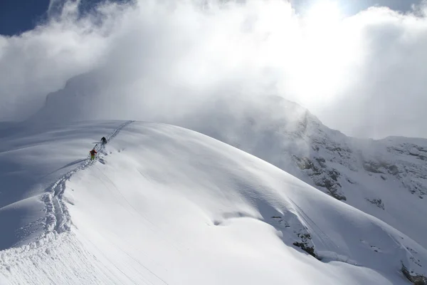 Skiërs een besneeuwde berg klimmen — Stockfoto