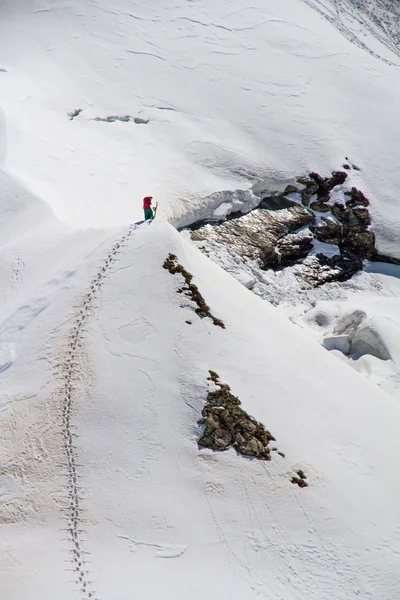 Skifahrer erklimmt einen verschneiten Berg — Stockfoto