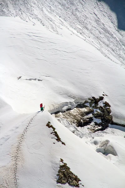 Esquiador escalando uma montanha nevada — Fotografia de Stock