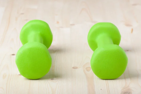 Mancuernas verdes pequeñas en la superficie de madera — Foto de Stock