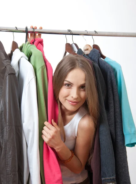 Ung kvinna nära rack med hängare — Stockfoto