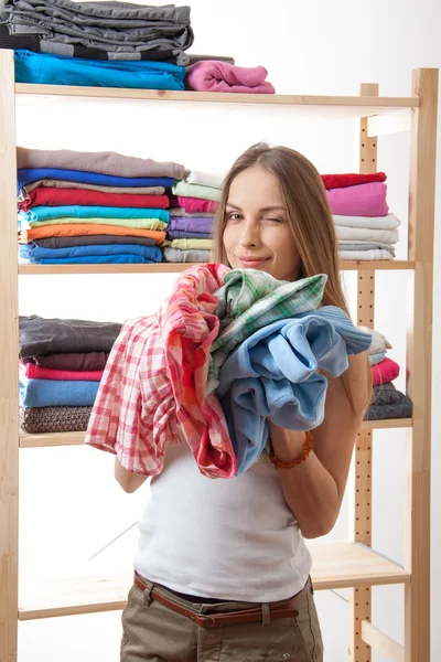 Junge Frau mit einem Stapel Kleidung — Stockfoto