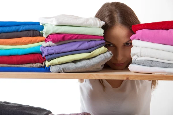 Junge Frau versteckt sich mit Kleidung hinter einem Regal — Stockfoto