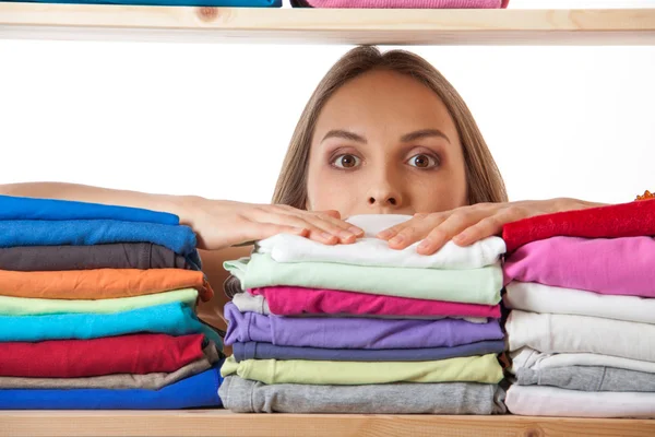 Mujer joven escondida detrás de un estante con ropa — Foto de Stock