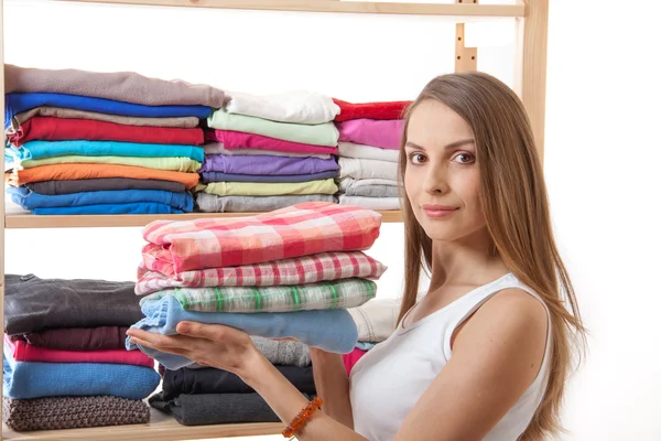 Jovem segurando uma pilha de roupas — Fotografia de Stock