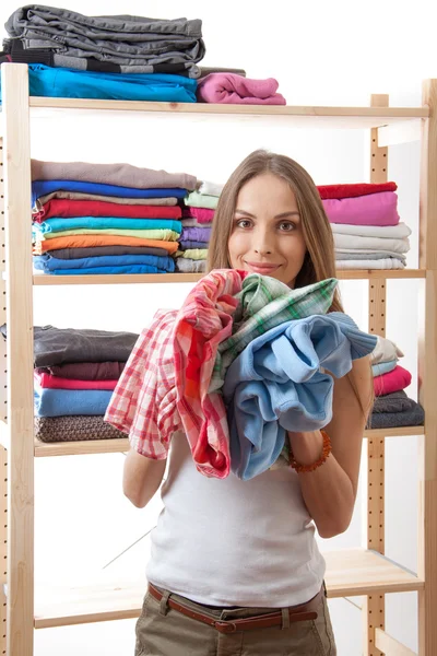 Young woman holding a pile of clothes — Stock Photo, Image