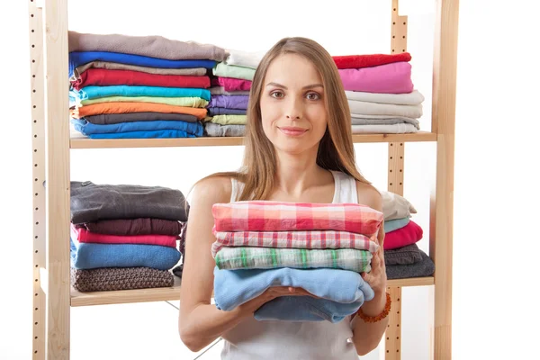 Junge Frau mit einem Stapel Kleidung — Stockfoto