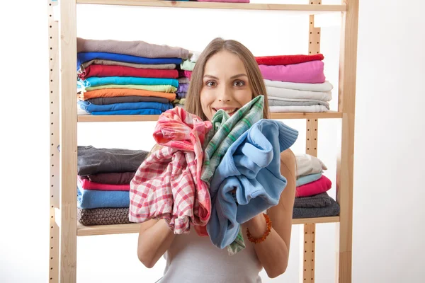 Junge Frau mit einem Stapel Kleidung — Stockfoto