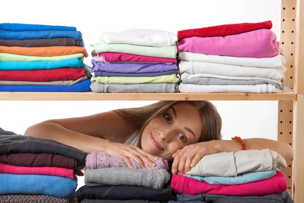 young woman hiding behind a shelf with clothing