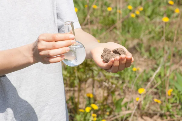 Terriccio secco in mano e una fiaschetta con acqua — Foto Stock