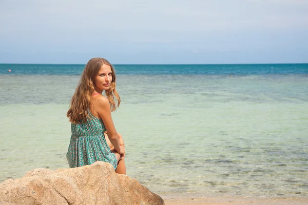 Chica en vestido sentado en una roca junto al mar —  Fotos de Stock