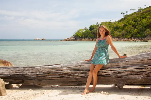Chica en vestido sentado en una roca junto al mar — Foto de Stock