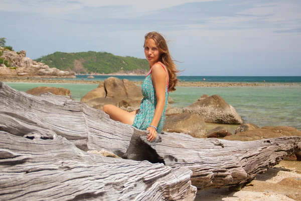 Meisje in jurk zittend op een rots aan de zee — Stockfoto