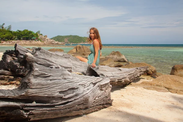 Mädchen in Kleid sitzt auf einem Felsen am Meer — Stockfoto