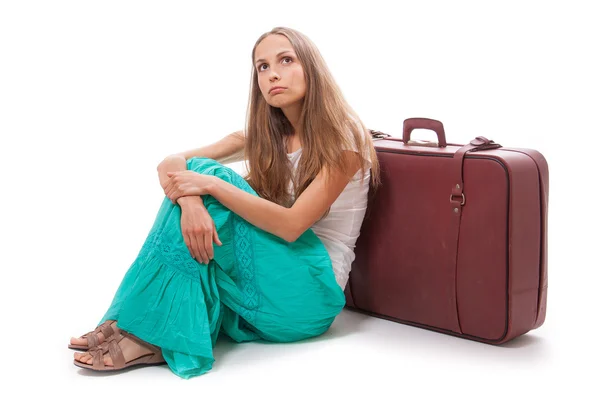 Fille assise près d'une valise, isolée sur blanc — Photo