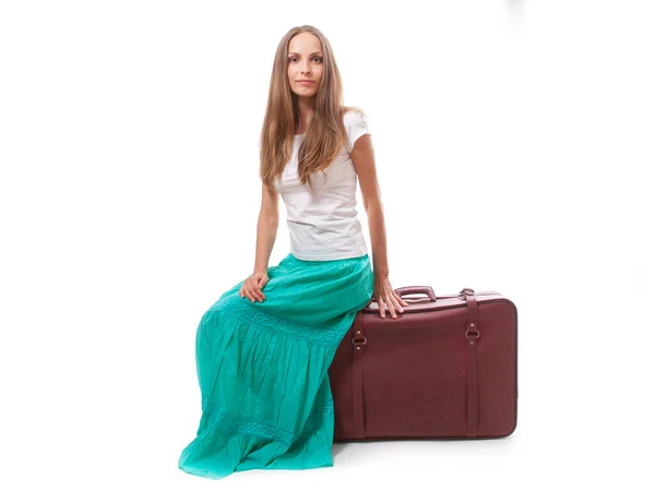 Молодая женщина сидит на чемодане — стоковое фото