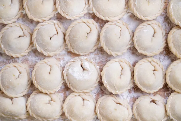 Carne o albóndigas vegetarianas, pelmeni en una tabla de madera. Comida nacional rusa. Vista superior cercana. —  Fotos de Stock