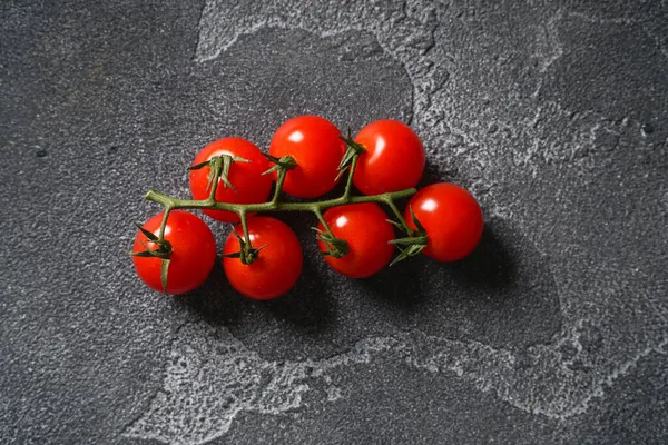 Ripe cherry tomatoes on a branch on a concrete background. Top view, copy space. — Stock Photo, Image