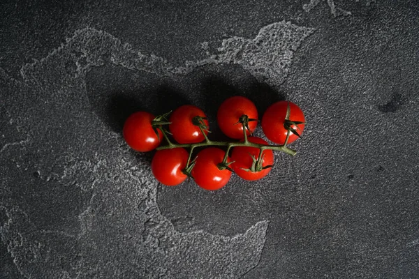 Ripe cherry tomatoes on a branch on a concrete background. Top view, copy space. — Stock Photo, Image