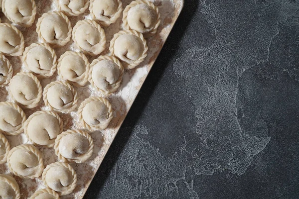 Las albóndigas de carne o vegetarianas, pelmeni en una tabla de madera sobre una mesa gris oscuro. Comida nacional rusa. Vista superior cercana. —  Fotos de Stock