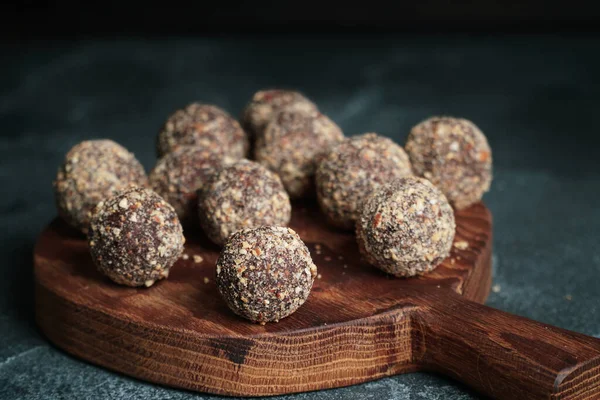 Gezonde zelfgemaakte energieballen op houten bord. Veganistische snoepjes, snoepjes gemaakt van noten en dadels. — Stockfoto