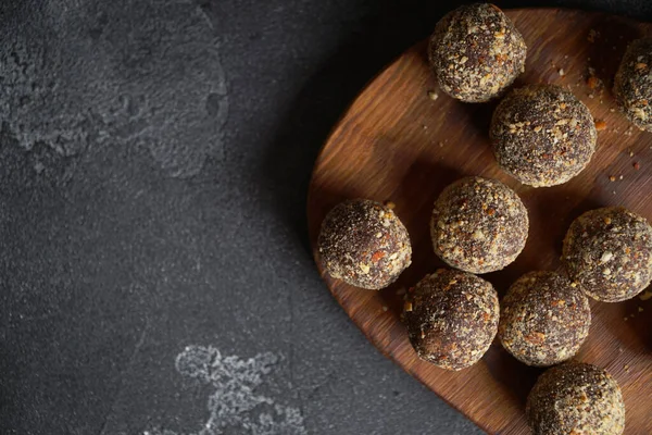 Healthy homemade energy balls on wooden plate. Vegan candies, sweets made of nuts and dates. — Stock Photo, Image
