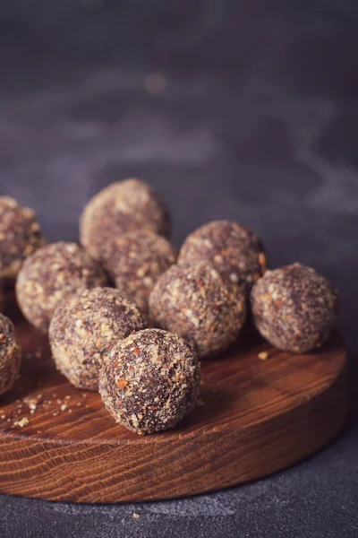 Gezonde zelfgemaakte energieballen op houten bord. Veganistische snoepjes, snoepjes gemaakt van noten en dadels. — Stockfoto