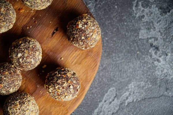 Gezonde zelfgemaakte energieballen op houten bord. Veganistische snoepjes, snoepjes gemaakt van noten en dadels. — Stockfoto