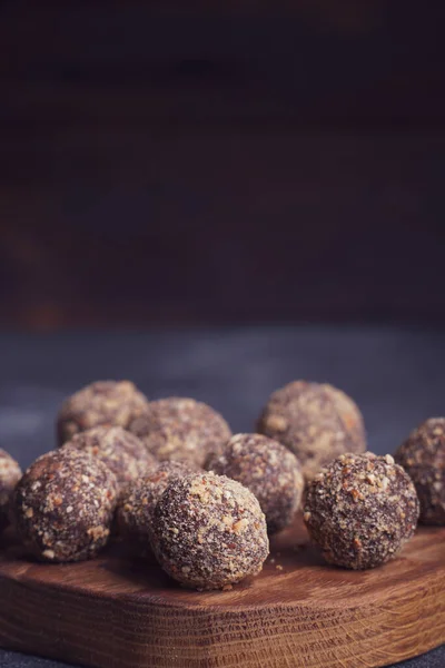 Gezonde zelfgemaakte energieballen op houten bord. Veganistische snoepjes, snoepjes gemaakt van noten en dadels. — Stockfoto