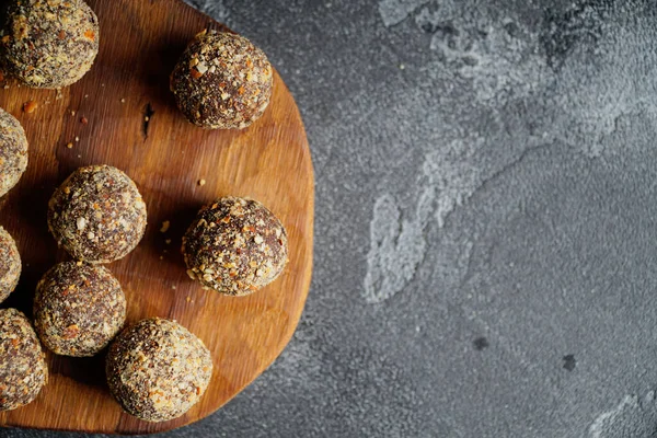 Gezonde zelfgemaakte energieballen op houten bord. Veganistische snoepjes, snoepjes gemaakt van noten en dadels. — Stockfoto