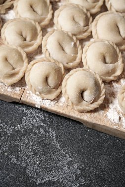 Et ya da vejetaryen hamur köftesi. Koyu gri bir masada tahta bir tahtada pelmeni. Rus ulusal yemeği. Üst görünümü kapat.