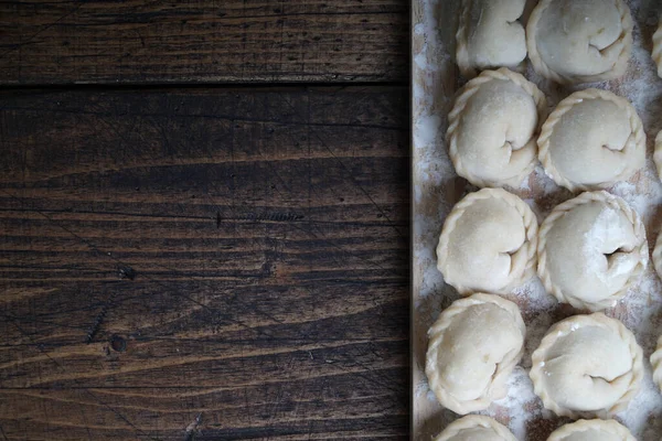 Mięso lub wegetariańskie pierogi, pelmeni na drewnianej desce. Rosyjskie jedzenie narodowe. Zamknij górny widok z przestrzenią do kopiowania. — Zdjęcie stockowe