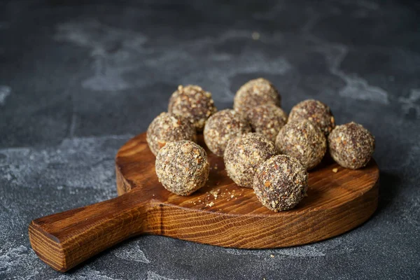 Gezonde zelfgemaakte energieballen op houten bord. Veganistische snoepjes, snoepjes gemaakt van noten en dadels. — Stockfoto