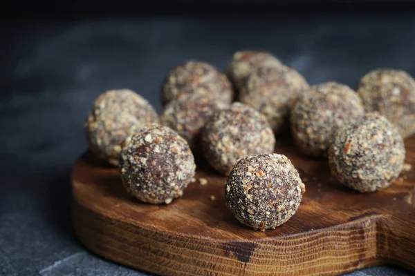 Zdravé domácí energetické koule na dřevěném talíři. Veganské bonbóny, sladkosti z ořechů a datlí. — Stock fotografie