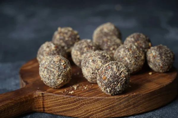 Gezonde zelfgemaakte energieballen op houten bord. Veganistische snoepjes, snoepjes gemaakt van noten en dadels. — Stockfoto