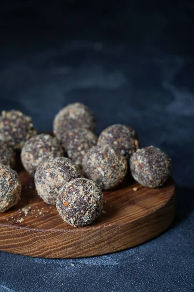 Gezonde zelfgemaakte energieballen op houten bord. Veganistische snoepjes, snoepjes gemaakt van noten en dadels. — Stockfoto