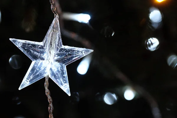 Luces blancas en el árbol de Navidad. Decoración en forma de estrella. Nochebuena brillante en la noche oscura. — Foto de Stock