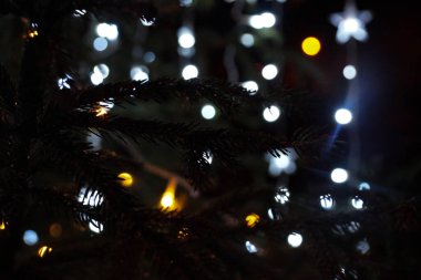 Noel ağacında beyaz ışıklar. Yıldız şeklinde dekorasyon. Karanlık gecede Parlak Noel arifesi.