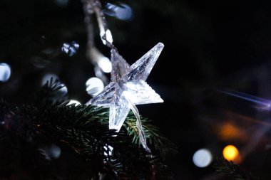 Noel ağacında beyaz ışıklar. Yıldız şeklinde dekorasyon. Karanlık gecede Parlak Noel arifesi.