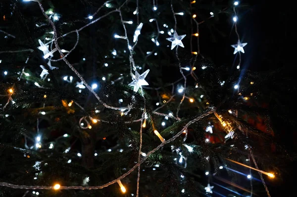 Luces blancas en el árbol de Navidad. Decoración en forma de estrella. Nochebuena brillante en la noche oscura. — Foto de Stock