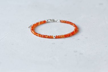 Carnelian bileziği. Doğal Carnelian taşlarından yapılmış bilezik. Doğal taşlardan yapılmış bilezik. El yapımı mücevherler. Hafif modern arkaplanda el yapımı bilezikler.