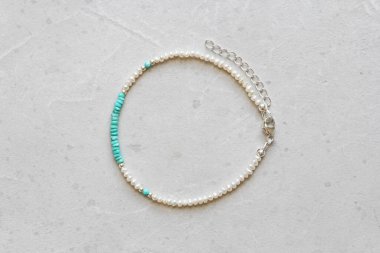 Turkuaz ve inci bilezik. Doğal taş turkuaz incilerden yapılma bilezik. Doğal taşlardan yapılmış bilezik. El yapımı mücevherler. Hafif modern arkaplanda el yapımı bilezikler.
